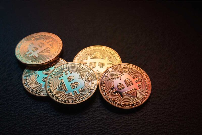 A conceptual image showing bitcoins over a black background.