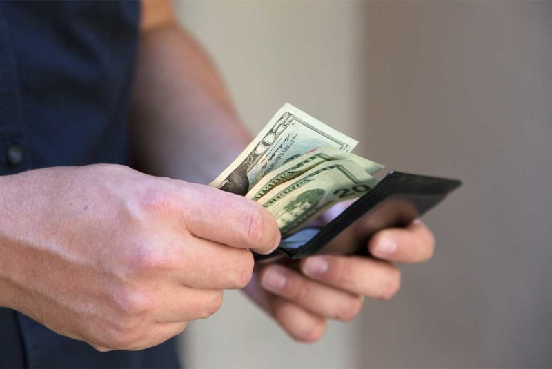 A person thumbs through cash from their wallet