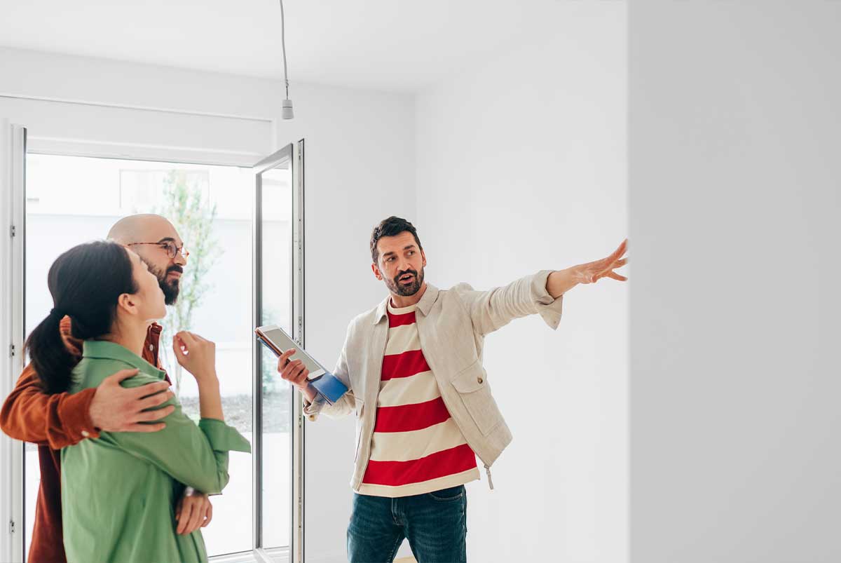 A real estate agent shows a home to a young couple.