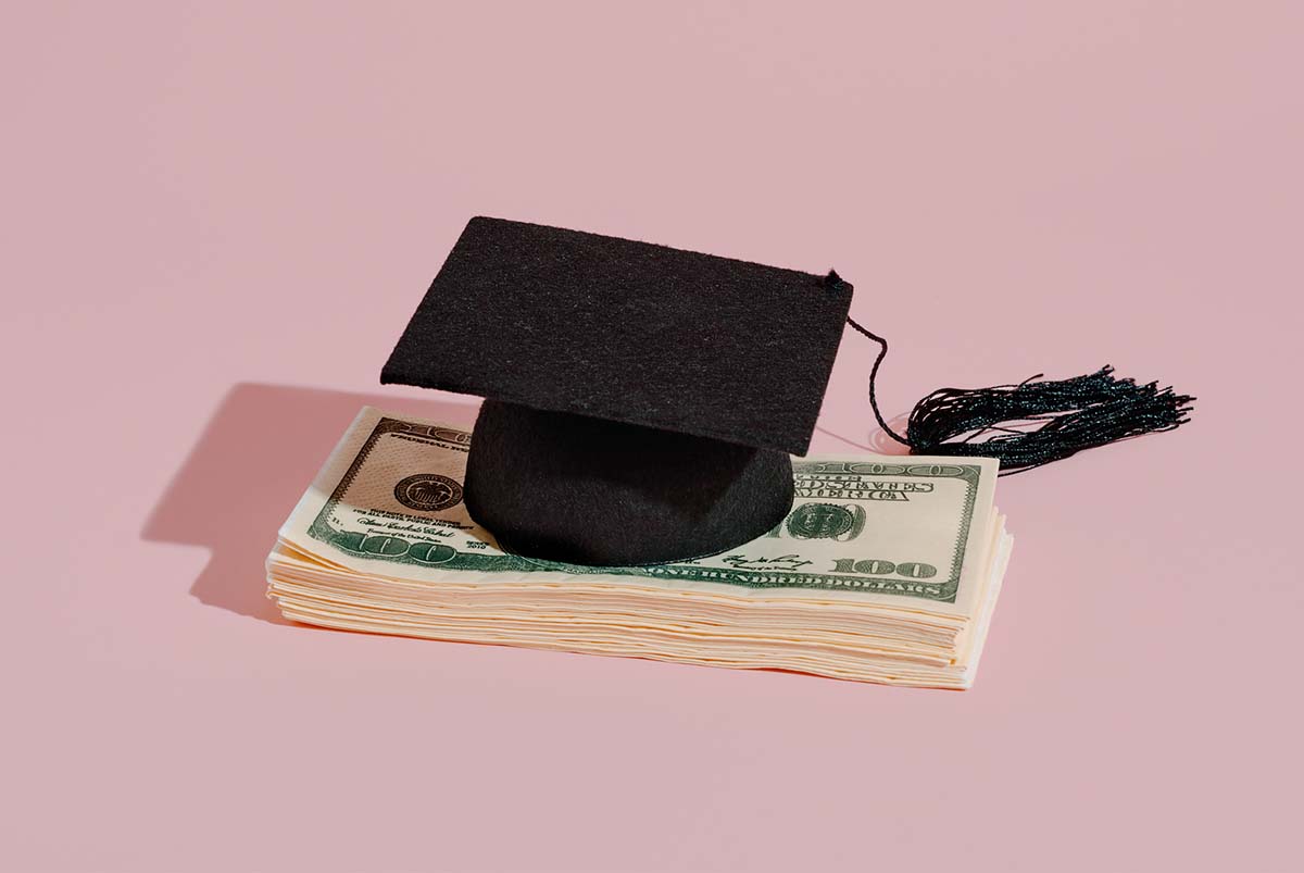 Graduation cap on top of a stack of money