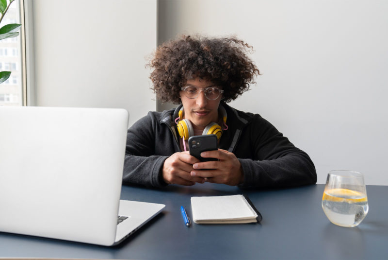 man with afro hair, yellow headphones on his phone trying to understand personal lines of credit
