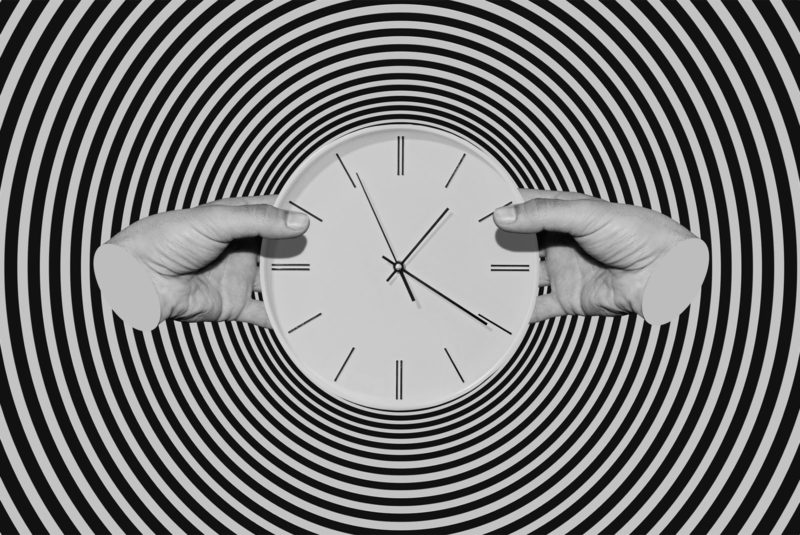 hypnotic black and white image of two hands holding a clock