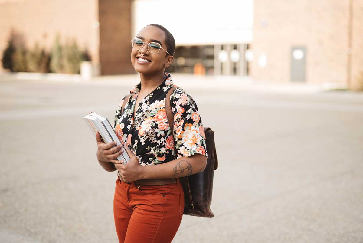 A student in a floral top holding textbooks