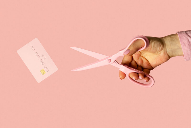 A metaphorical image of hands cutting a credit card, meant to represent getting out of credit card debt.