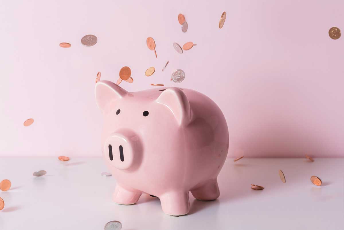 Pink piggy bank with coins falling around it.