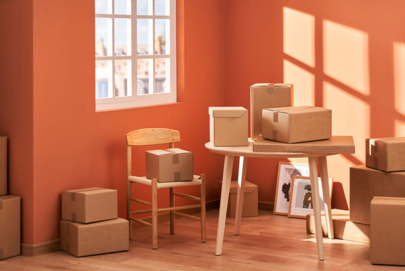 Boxes packed and taped stacked loosely in a bright room