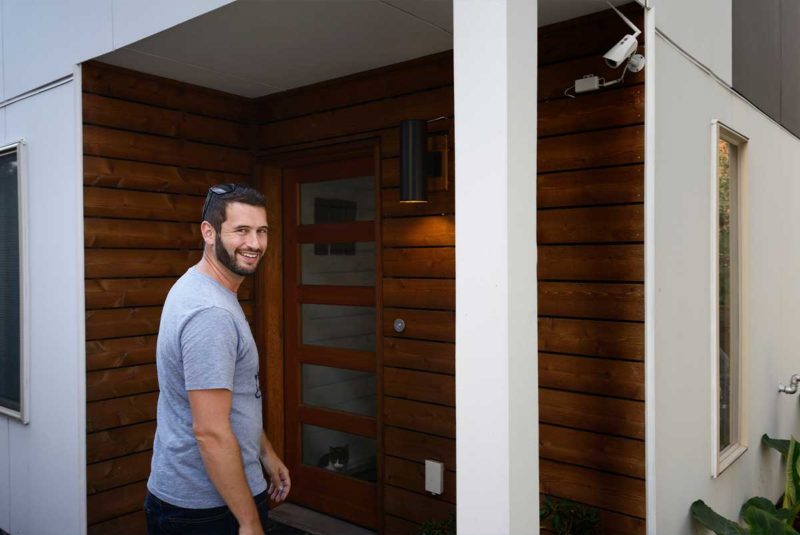 Man smiling while walking up to the front door of a house
