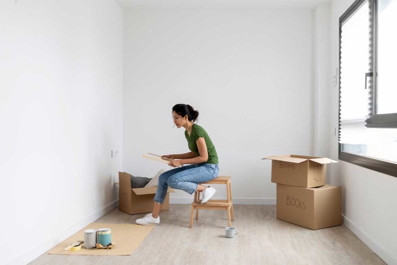 A young woman unpacking moving boxes in her new home