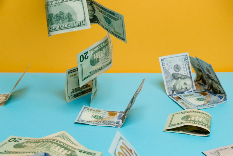 Yellow background and blue table with money falling on it