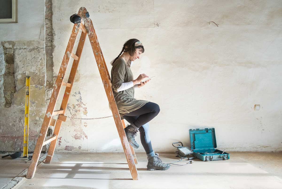 woman on phone leaning up against a ladder