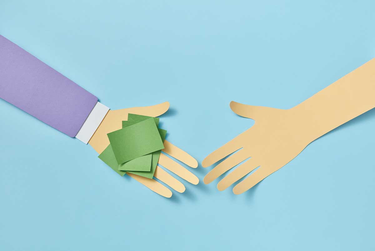 Two paper cut outs of arms and hands with one hand holding green sticky notes