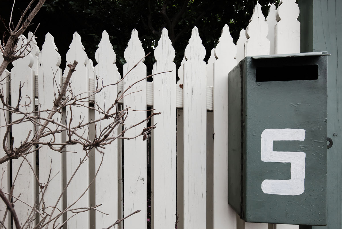 Number 5 on mailbox with white picket fence behind it