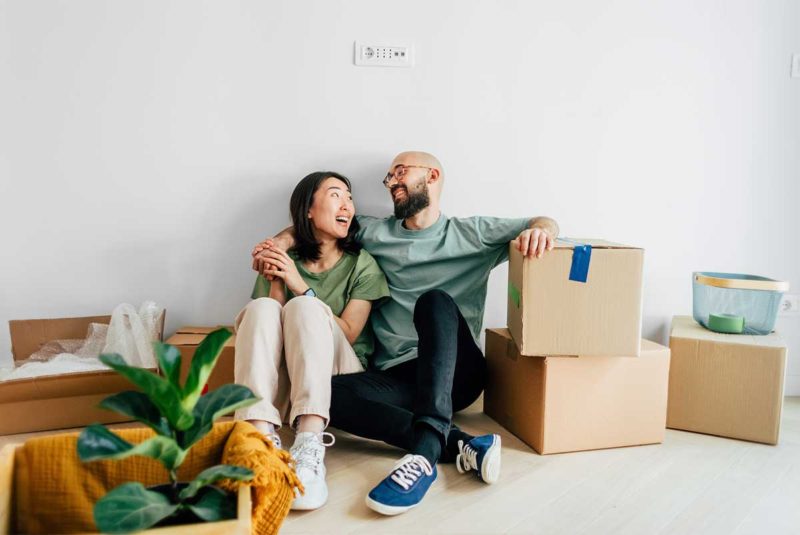 Couple sitting on the floor laughing with moving boxes