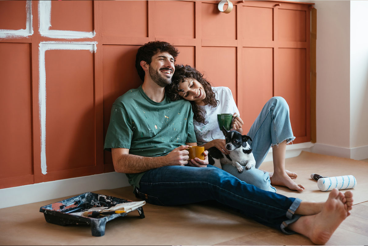 Cheerful couple with dog in renovated room
