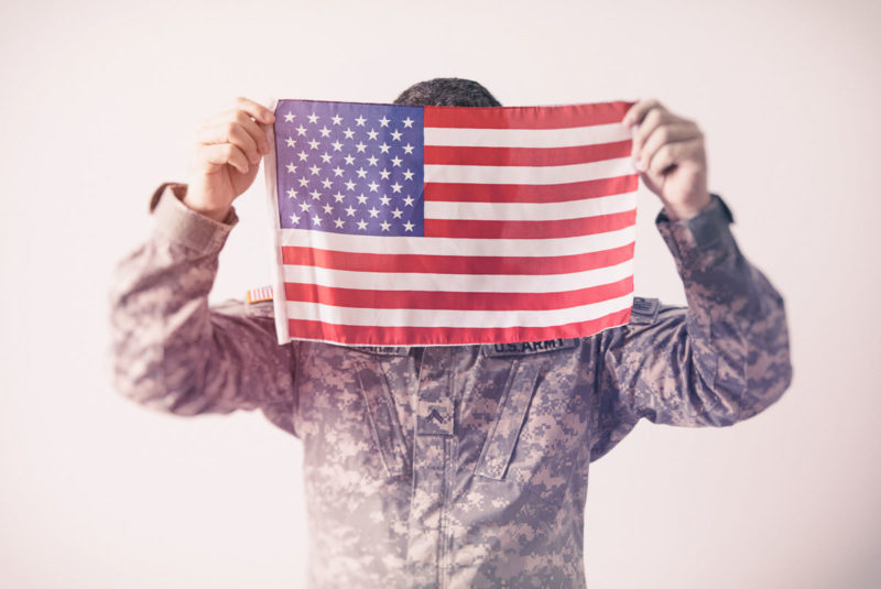 Military Man Holding Up United States Flag