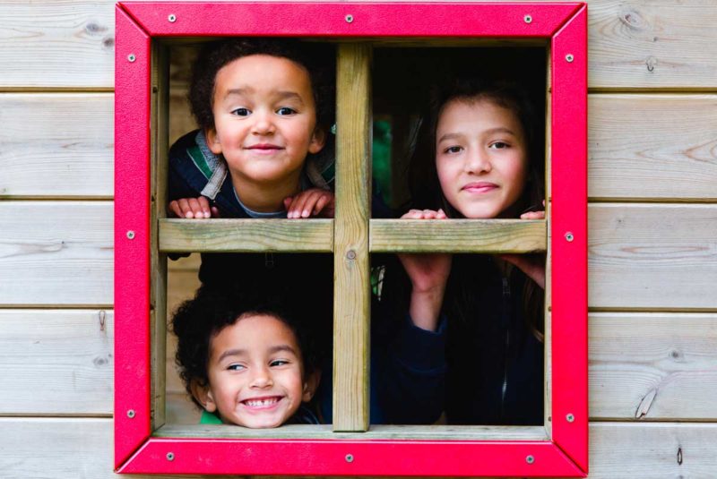 Three siblings looking out playhouse window