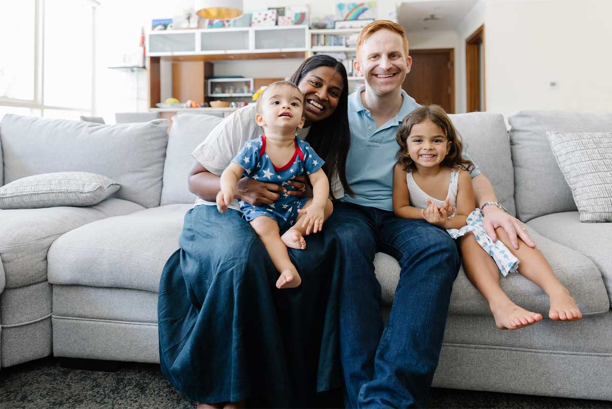 Family with two children sitting on the couch together smiling