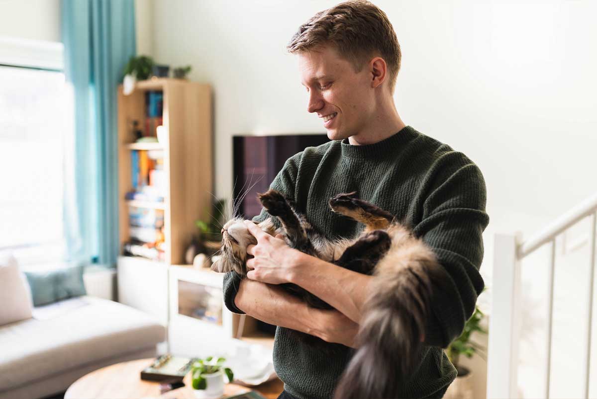 Man holding cat and smiling in his living room