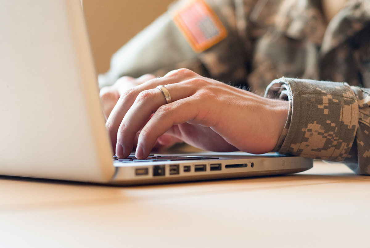 Closeup of hands of a soldier using a laptop