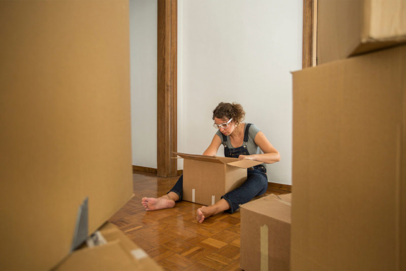 lady in dungarees looking inside a box for help as a first time homebuyer